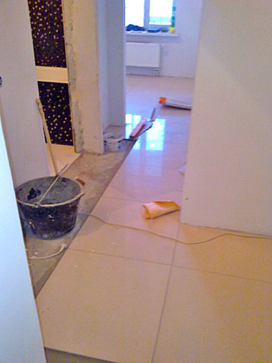 Глянцевый керамогранит 60х60 см в узком коридоре. При такой раскладке будет некрасивая подрезка вдоль всей стены. В таком помещении лучше выбрать плитку меньшего формата. Глянцевая поверхность очень скользкая, особенно по мокрому полу.