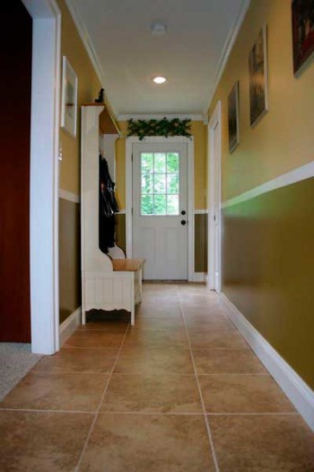 Стандартная плитка под камень отлично гармонирует с жёлто-зелёными стенами. Раскладка расположена равномерно от центра, поэтому крайние подрезки не выделяются.